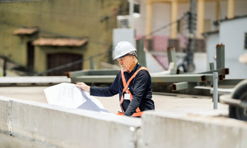 Shot of a senior engineer reviewing blueprint at construction site